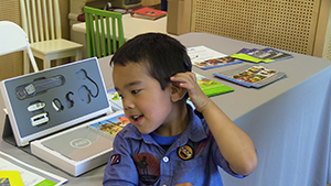 Kisan sitting at a table with audiological equipment behind him